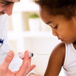 Young girl receives immunization shot from physician