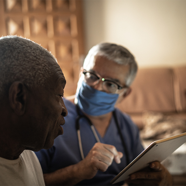 Health visitor and a senior man during home visit - using digital tablet