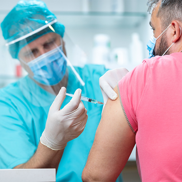 Doctor wearing protective workwear injecting vaccine into patient's arm